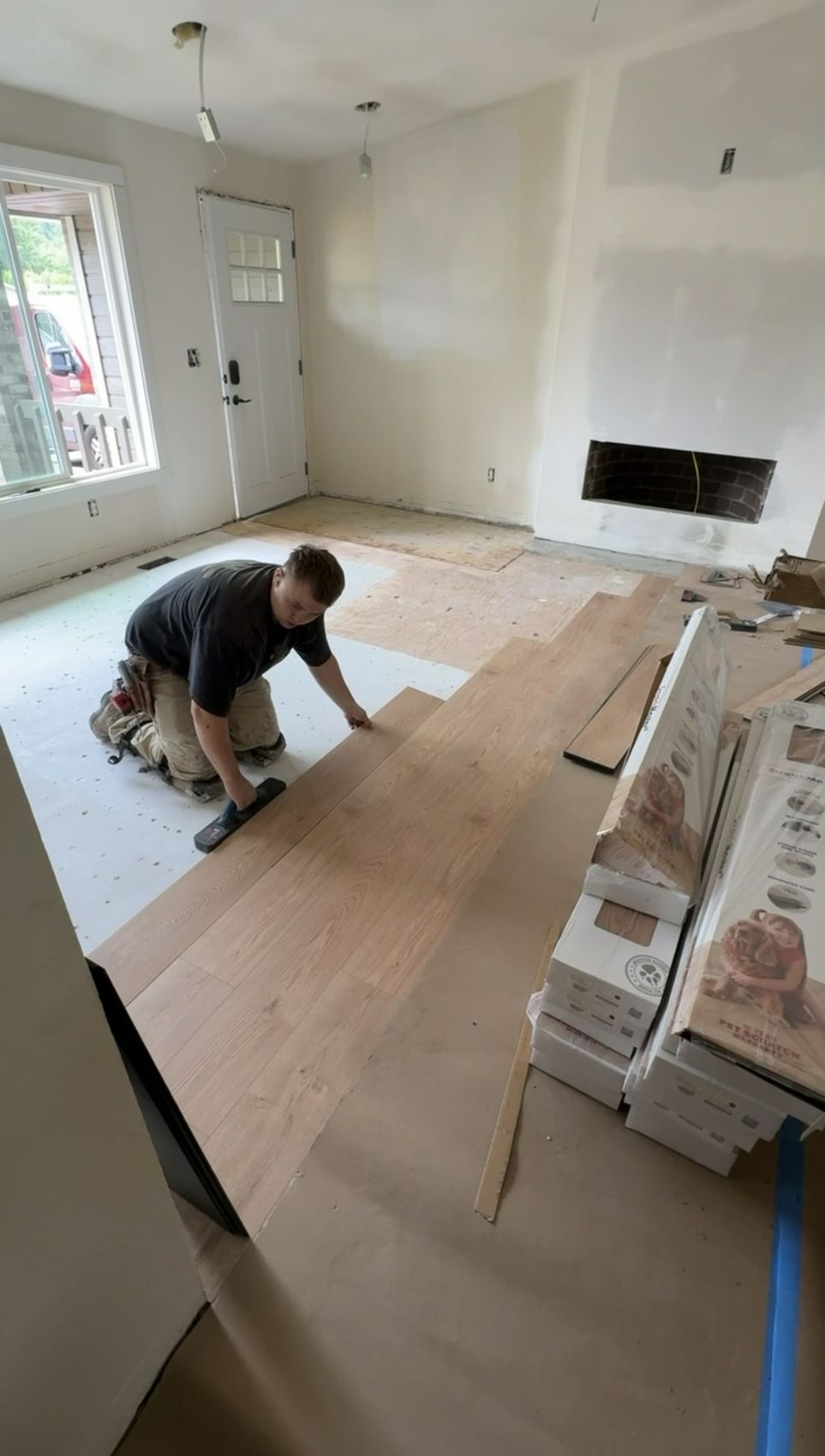 PNW Floors installer locking laminate planks together over underlayment in a living room