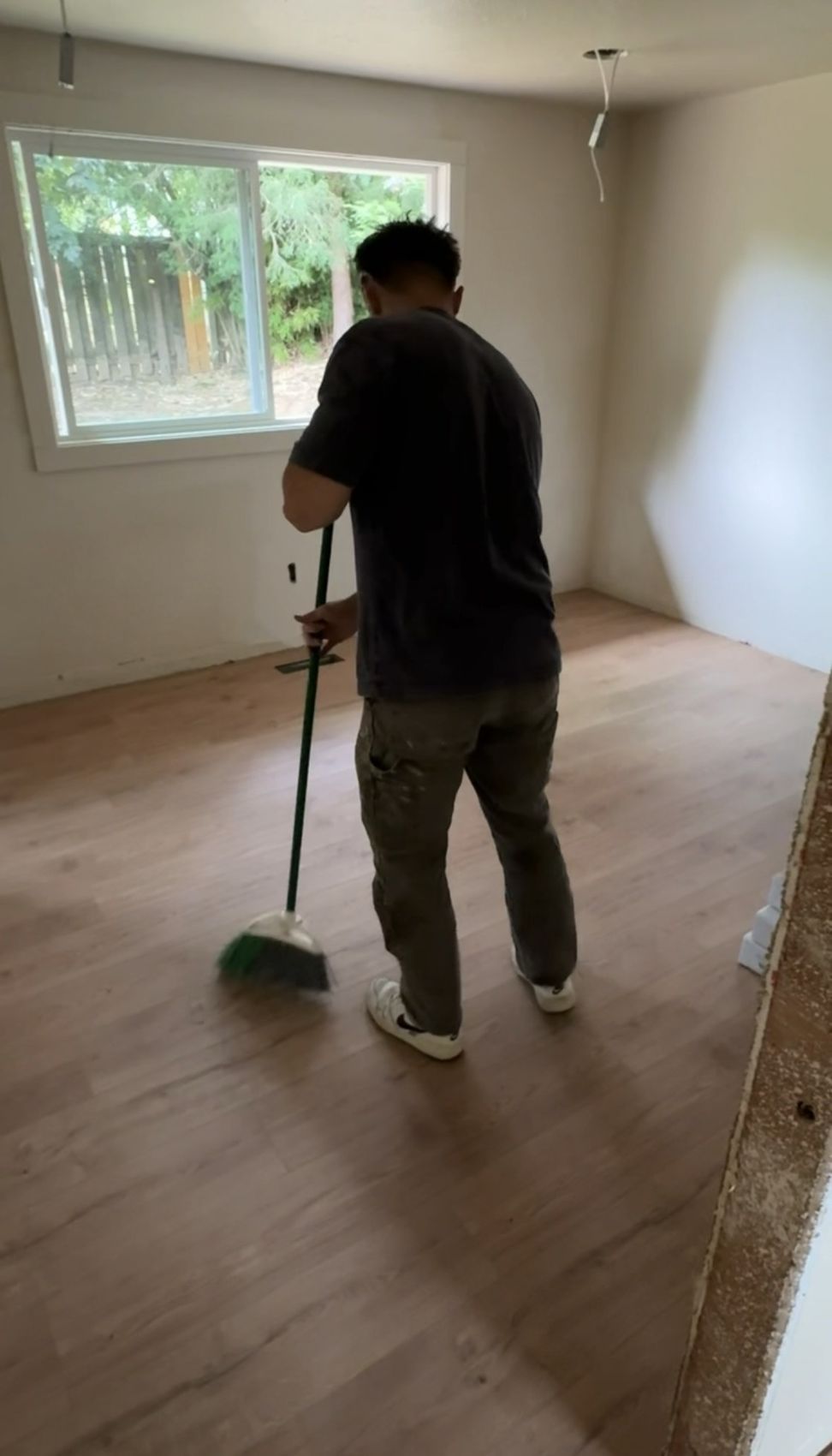 Newly installed luxury vinyl plank flooring in an empty bedroom being swept after install