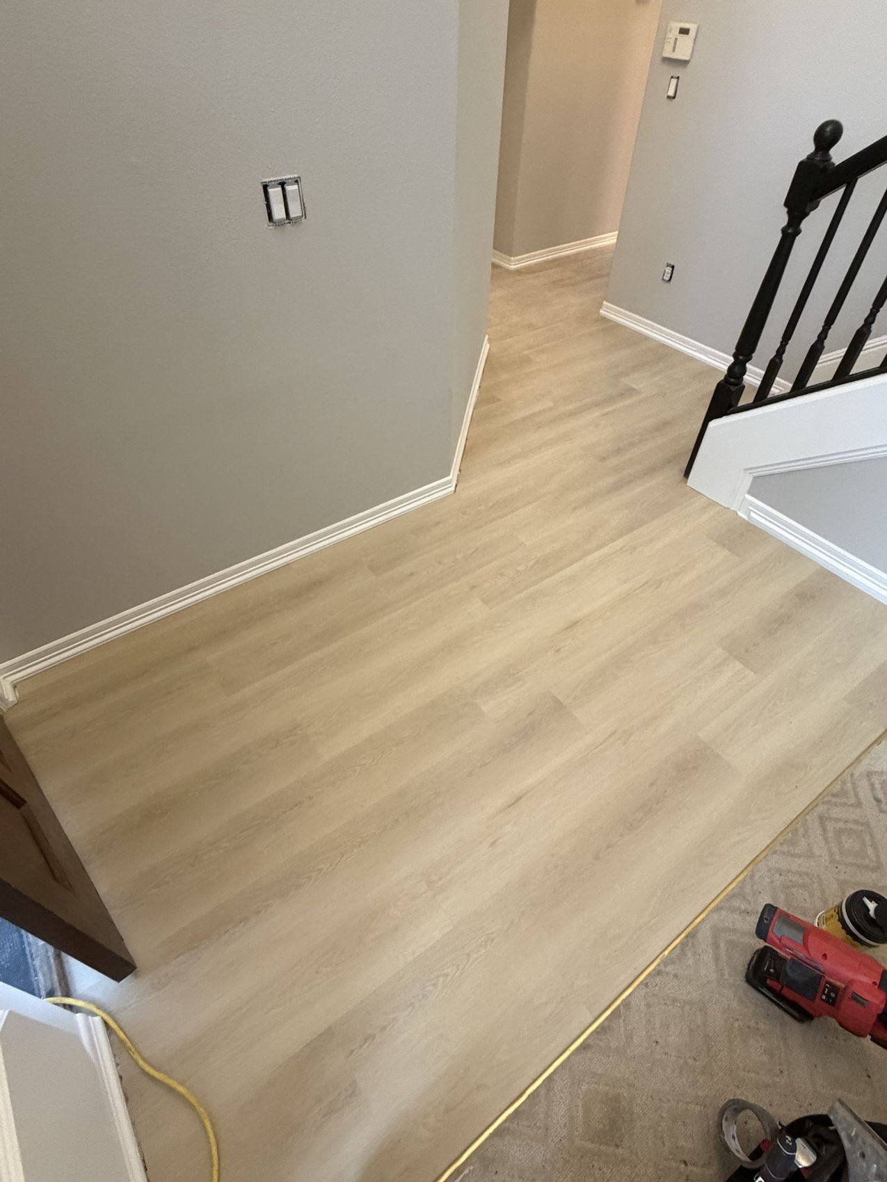 Light oak luxury vinyl plank through a hallway and stair landing with new white baseboard
